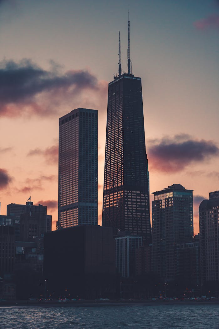 Facade of contemporary glass skyscrapers located in coastal urban city area and reflecting pink evening sky